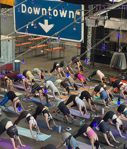 Yoga Social community class at a Denver brewery with purple string lights
